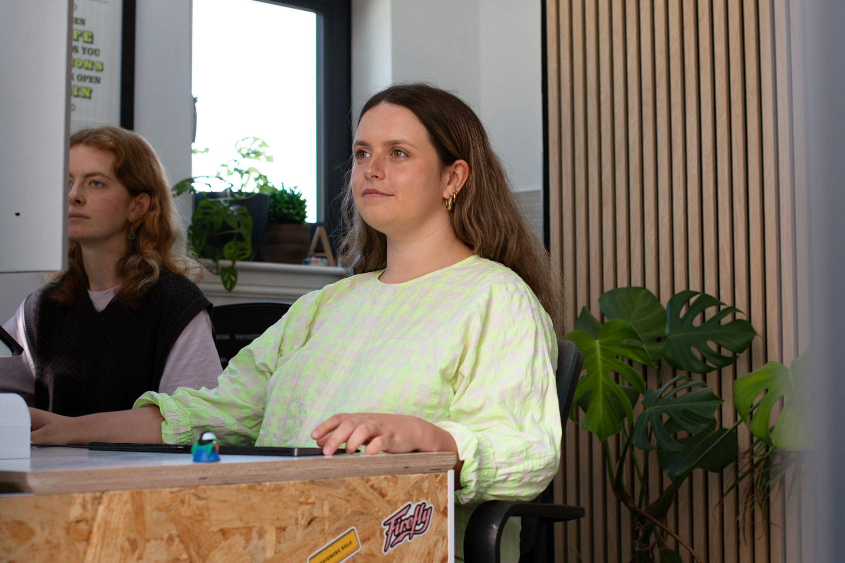 A shot of Firefly's Graphic Designer Charlotte Henderson sat on a desk working on a computer.